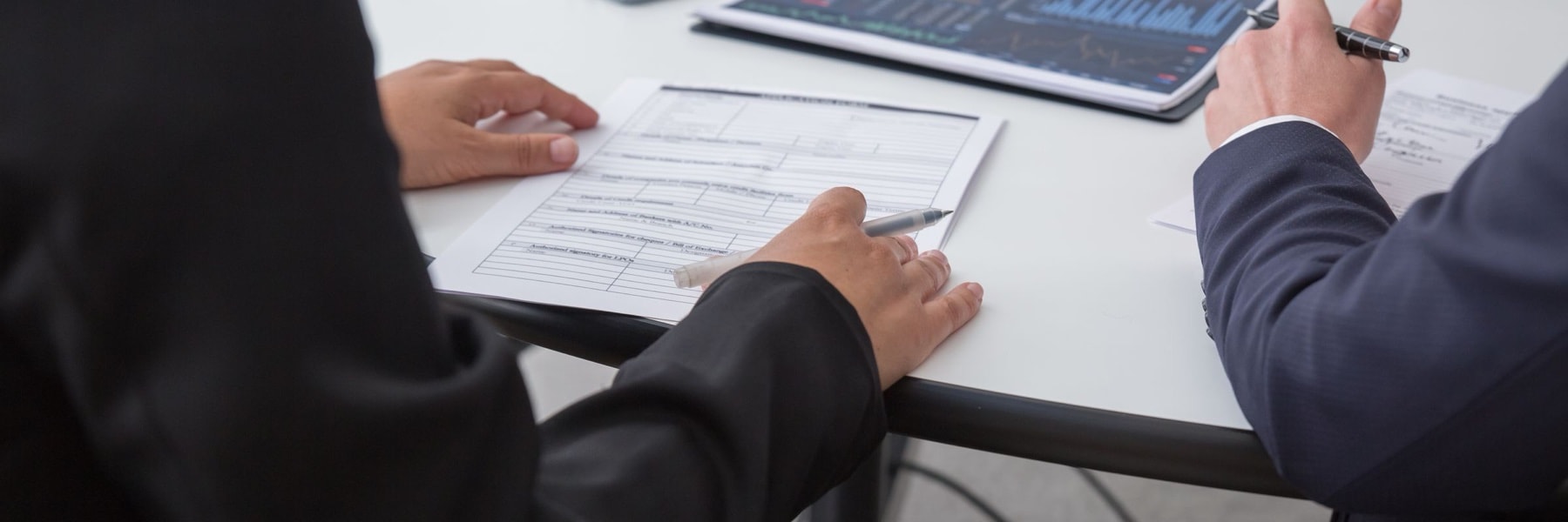 Dos personas revisan un formulario impreso sobre una mesa, junto a un informe con gráficos.